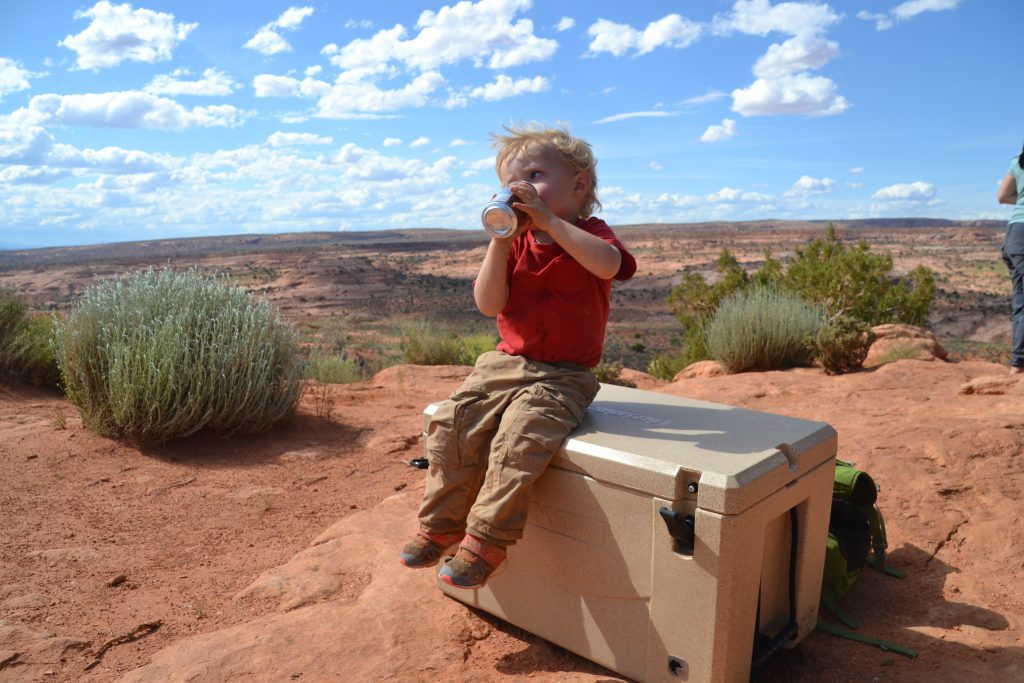 boy sitting on cooler in the desert