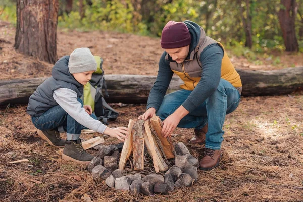 Father and son preparing firewood to start their campfire